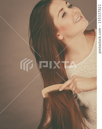 Happy woman brushing her hair Happy woman brushing her hair 135337821