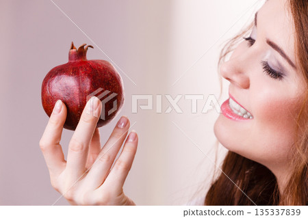 Cheerful woman holds pomegranate fruits Cheerful woman holds pomegranate fruits 135337839