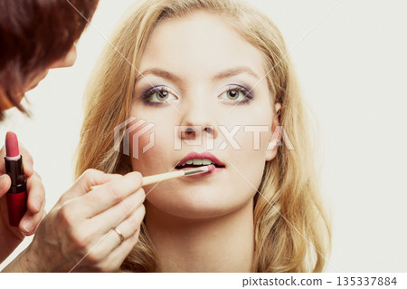 Makeup. Woman applying red lipstick with brush Makeup. Woman applying red lipstick with brush 135337884