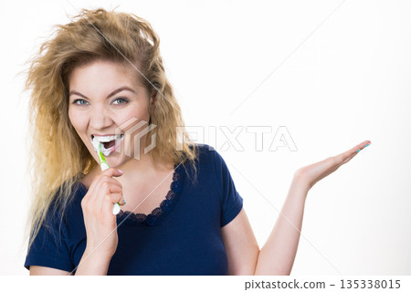 Woman brushing teeth holds open hand Woman brushing teeth holds open hand 135338015
