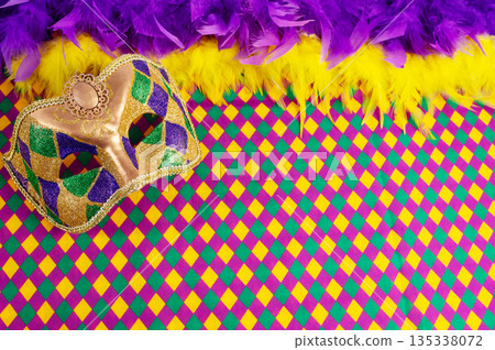 Top view of a beautiful composition of colorful masks, confetti, Mardi Gras decorations. Yellow Mardi Gras banner. 135338072