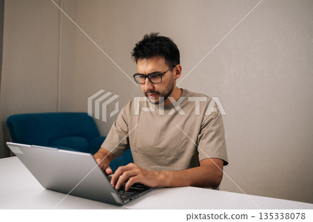 Portrait of successful programmer male working typing code on laptop keyboard, showcasing process of software development and coding expertise. Concept of remote workplace. Portrait of successful programmer male working typing code on laptop keyboard, showcasing process of software development and coding expertise. Concept of remote workplace. 135338078