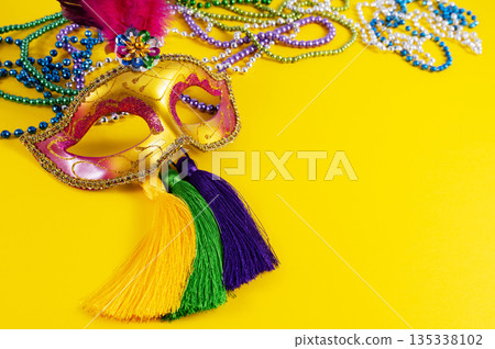 Top view of a beautiful composition of colorful masks, confetti, Mardi Gras decorations. Yellow Mardi Gras banner. 135338102
