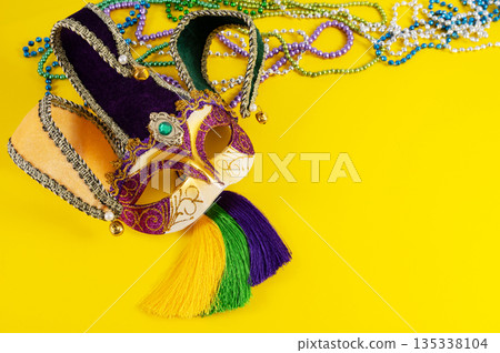 Top view of a beautiful composition of colorful masks, confetti, Mardi Gras decorations. Yellow Mardi Gras banner. 135338104