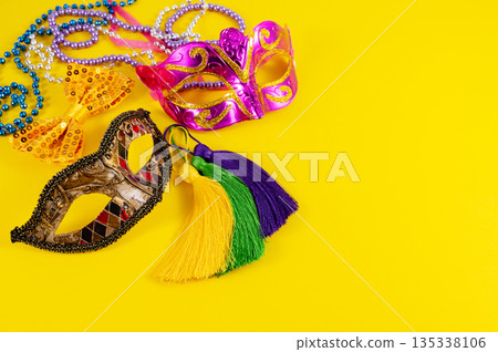 Top view of a beautiful composition of colorful masks, confetti, Mardi Gras decorations. Yellow Mardi Gras banner. Top view of a beautiful composition of colorful masks, confetti, Mardi Gras decorations. Yellow Mardi Gras banner. 135338106