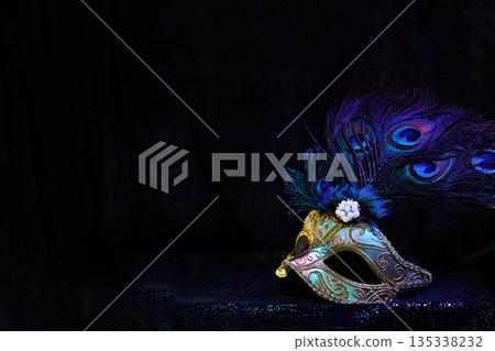 Venetian masquerade mask with peacock feathers on dark background 135338232