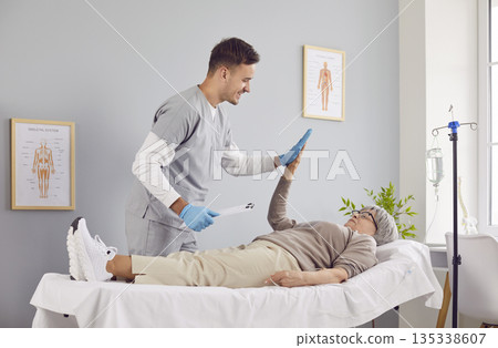 Friendly doctor gives high five to senior woman who is receiving vitamin IV drip 135338607