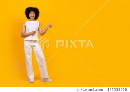 Full body portrait of young black woman pointing aside at copy space 135338936
