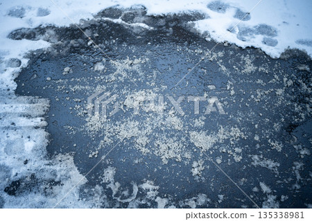 Deicing chemicals on snowy street in winter. Slippery road sprinkled with technical salt Deicing chemicals on snowy street in winter. Slippery road sprinkled with technical salt 135338981