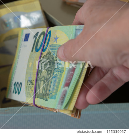 Saving cash in a metal box. Human hand with brick of euro notes 135339037