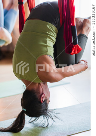 Woman practicing aerial yoga anti-gravity pose Woman practicing aerial yoga anti-gravity pose 135339167