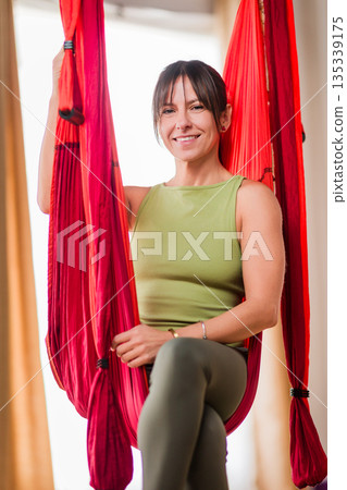 Woman smiling relaxing in aerial yoga hammock 135339175
