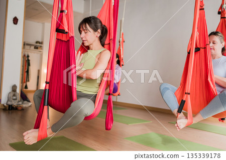 Woman practicing aerial yoga with hammock in class 135339178