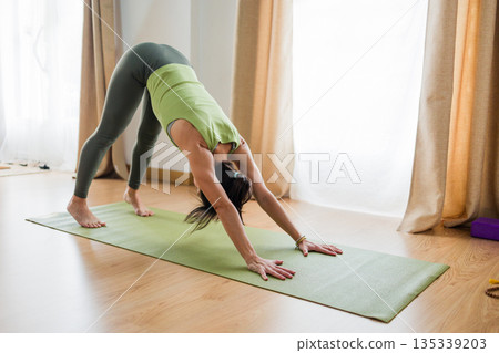 Hispanic woman performing downward facing dog yoga pose, adho mukha svanasana Hispanic woman performing downward facing dog yoga pose, adho mukha svanasana 135339203