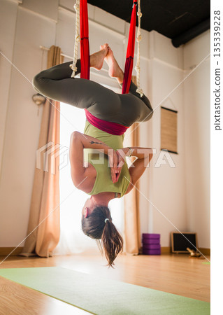 Woman practicing aerial yoga inversion in hammock class 135339228