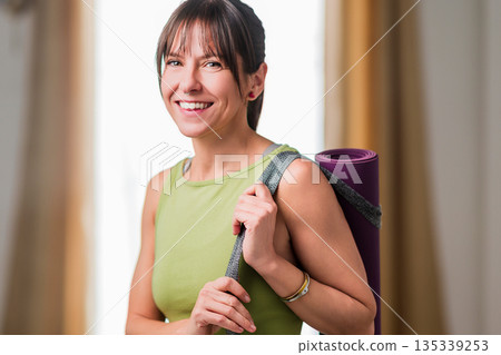 Happy woman carrying yoga mat preparing for wellness Happy woman carrying yoga mat preparing for wellness 135339253