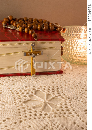 Rosary beads draped over a red religious book, symbolizing spiritual reflection 135339638