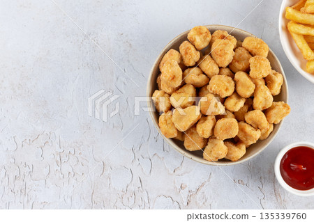 Popcorn chicken with ketchup and French fries on white plate, against a white background. Fast food.Top view. Copy space Popcorn chicken with ketchup and French fries on white plate, against a white background. Fast food.Top view. Copy space 135339760