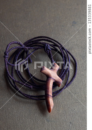 Wooden cross on a purple cord, representing Christian faith and devotion Wooden cross on a purple cord, representing Christian faith and devotion 135339881