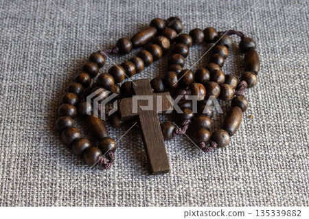 Wooden rosary beads with a simple cross on a grey backdrop, representing Christian faith Wooden rosary beads with a simple cross on a grey backdrop, representing Christian faith 135339882
