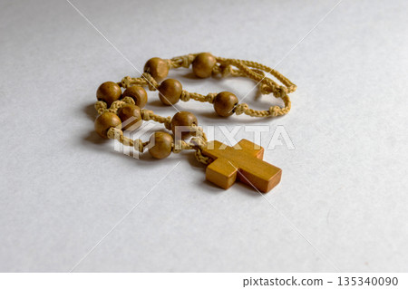 Wooden rosary beads with a simple cross on a white background,symbolizing Catholic faith Wooden rosary beads with a simple cross on a white background,symbolizing Catholic faith 135340090