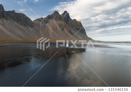 The jagged Vestrahorn mountains rise above a reflective black sand beach on Iceland's Stokksnes Peninsula, with a solitary figure adding scale. The jagged Vestrahorn mountains rise above a reflective black sand beach on Iceland's Stokksnes Peninsula, with a solitary figure adding scale. 135340150