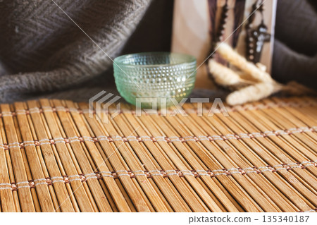 Bamboo mat with a textured glass bowl and dried plants creating a spiritual altar Bamboo mat with a textured glass bowl and dried plants creating a spiritual altar 135340187