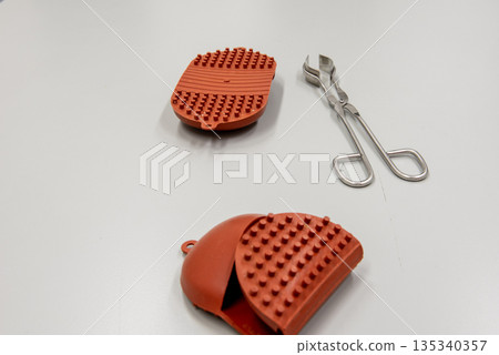 silicone hot pads and forceps on gray table in laboratory. silicone hot pads and forceps on gray table in laboratory. 135340357