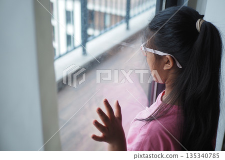 Girl looks out the window and touches the glass Girl looks out the window and touches the glass 135340785