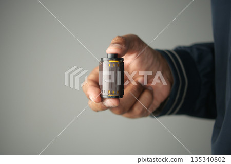 Holding a roll of film in a hand indoors 135340802
