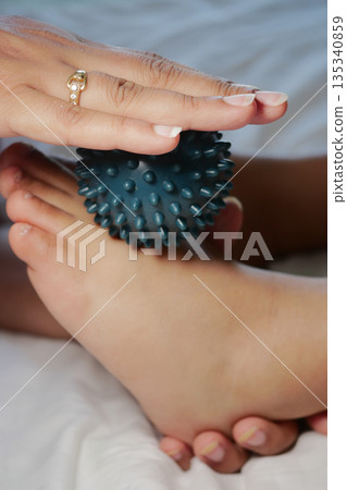 A child receives a foot massage with a spiky ball on their foot A child receives a foot massage with a spiky ball on their foot 135340859
