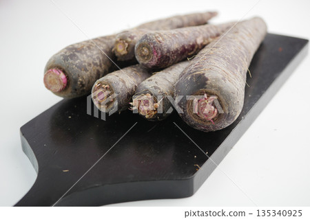Root vegetables placed on a wooden board in a kitchen 135340925