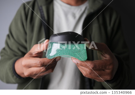 Person holds clear container of gel in indoor space 135340966