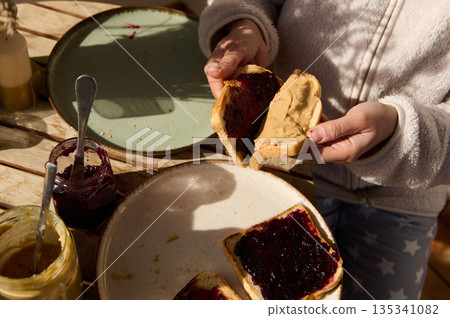 Hands Spread Peanut Butter And Jam On Bread During Outdoor Breakfast Picnic 135341082