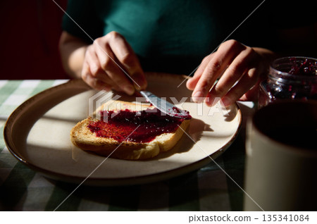 Person Spreading Jam On Toast At Breakfast Table For Peanut Butter And Jelly Day Person Spreading Jam On Toast At Breakfast Table For Peanut Butter And Jelly Day 135341084