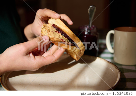 Hands Holding Peanut Butter And Jelly Sandwich For Breakfast On A Cozy Morning 135341085