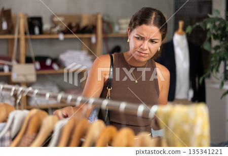 Distressed young woman customer in sales area of clothing store Distressed young woman customer in sales area of clothing store 135341221