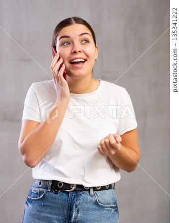 Smiling young woman talking on mobile phone Smiling young woman talking on mobile phone 135341222