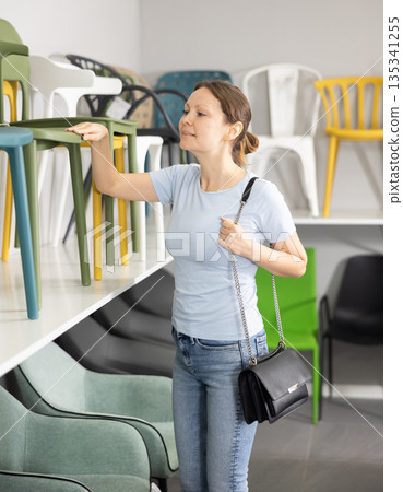 In furniture store, woman considering choose chairs for completing office suite In furniture store, woman considering choose chairs for completing office suite 135341255