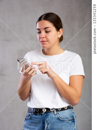 Calm young woman looking interestedly at mobile 135341259