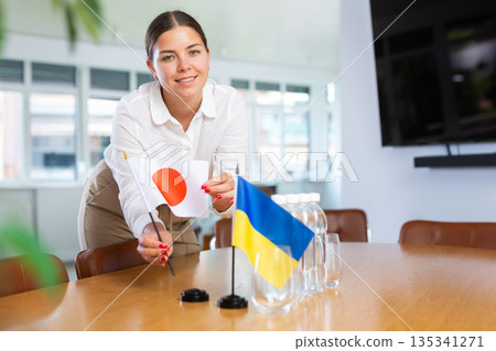 Young lady sets miniatures flags of Ukraine and Japan for international negotiations Young lady sets miniatures flags of Ukraine and Japan for international negotiations 135341271