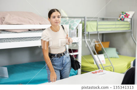 Positive young woman choosing new upholstered furniture in furniture store Positive young woman choosing new upholstered furniture in furniture store 135341313
