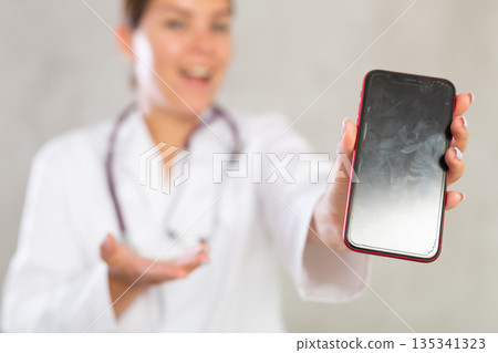 Young woman posing in medical uniform with phone 135341323