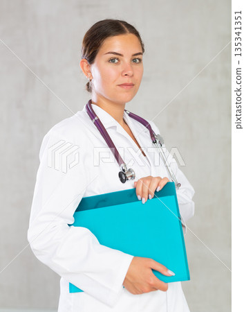 Young woman posing in medical uniform with folder Young woman posing in medical uniform with folder 135341351