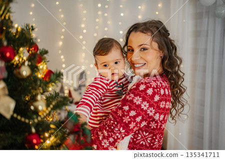 Mother holding baby celebrating Christmas at home Mother holding baby celebrating Christmas at home 135341711