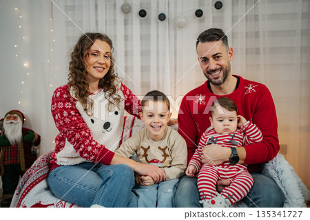 Happy family celebrating Christmas wearing matching sweaters at home Happy family celebrating Christmas wearing matching sweaters at home 135341727