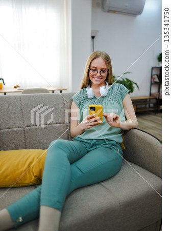 Woman relaxes with phone in cozy living room 135341750