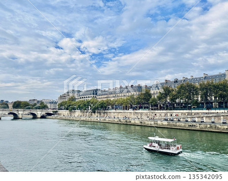 Tourist boats sailing along the Seine River in Paris, France, with the historic streets Tourist boats sailing along the Seine River in Paris, France, with the historic streets 135342095