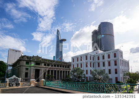 Ho Chi Minh City, Vietnam - June 23, 2025: A panoramic view of Ho Chi Minh City, Vietnam, showcasing historical French colonial architecture contrasting with the modern Bitexco Financial Tower. Ho Chi Minh City, Vietnam - June 23, 2025: A panoramic view of Ho Chi Minh City, Vietnam, showcasing historical French colonial architecture contrasting with the modern Bitexco Financial Tower. 135342391