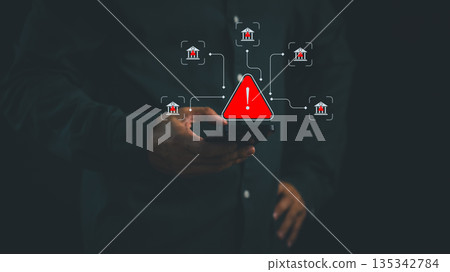 Person holding smartphone with warning alert and bank icon, symbolizing online banking fraud, financial scam, cybersecurity risk, and digital safety awareness in mobile transaction and fintech system. Person holding smartphone with warning alert and bank icon, symbolizing online banking fraud, financial scam, cybersecurity risk, and digital safety awareness in mobile transaction and fintech system. 135342784